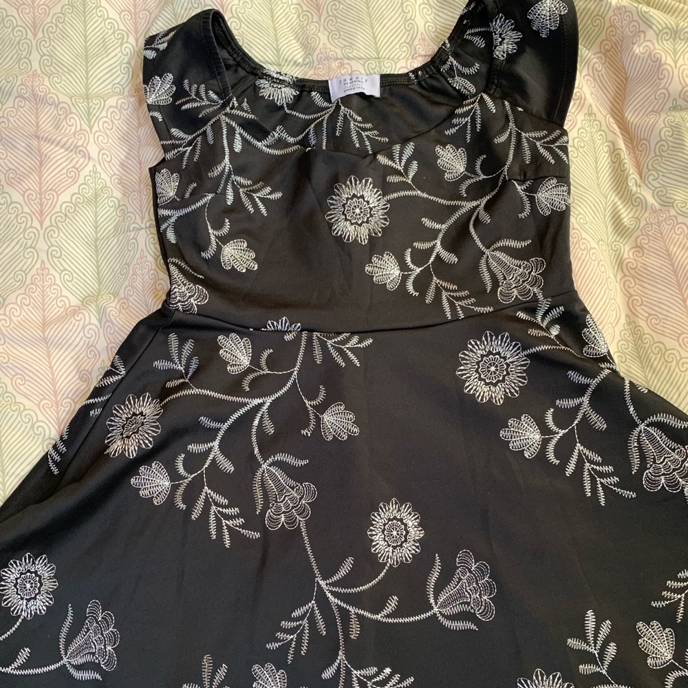 A short black dress with white flowers pattern on it.